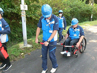 避難困難者の車椅子を引いてサポートしている写真